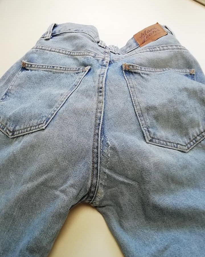 Przetarcie i rozdarcie jeansów w kroku przy szwie siedzenia przed naprawą